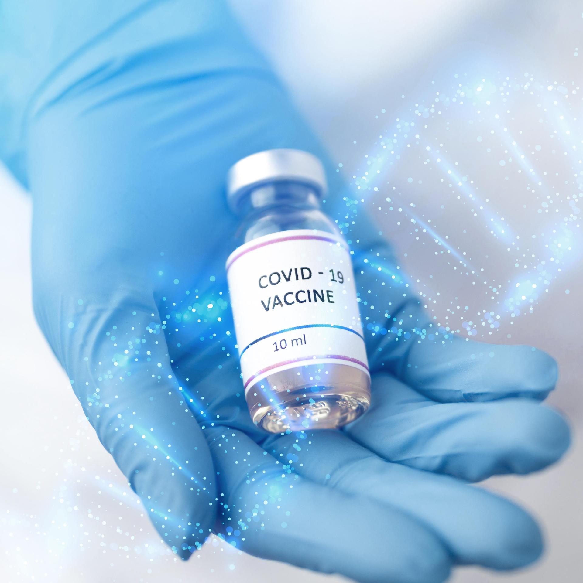 Blue-gloved hand holding a Covid-19 vaccine vial
