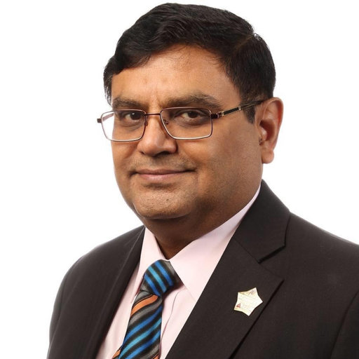 South Asian man in brown suit, colourful striped tie and glasses