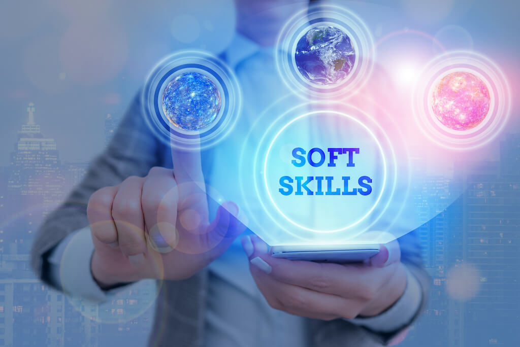 Man with finger on digital screen with the words "soft skills" in bold